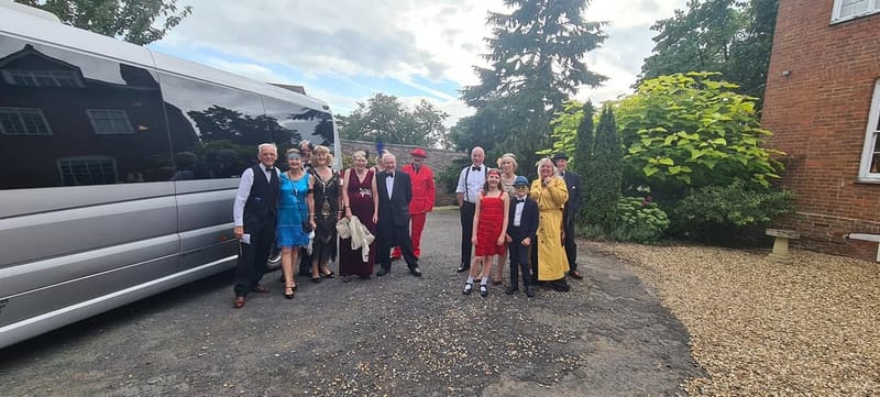 A dressed-up party gathered beside a Mawley Minibus before a night out