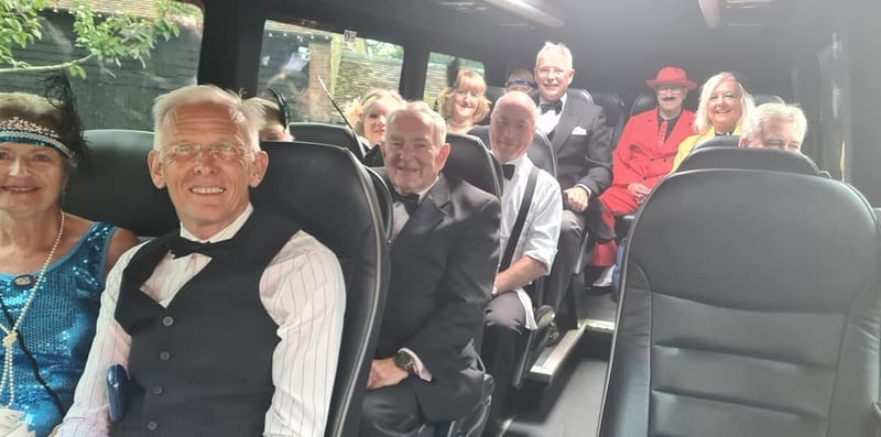 Smiling passengers in 1920s fancy dress on board a Mawley Minibus